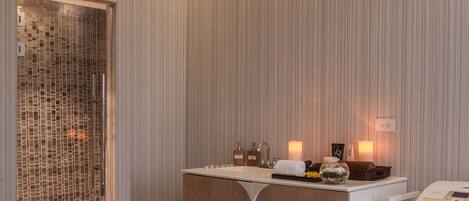 A modern hotel room with a large bed, a vanity with a mirror, and a small seating area.