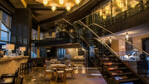 Un vestíbulo amplio con una escalera, zona de estar y un bar.