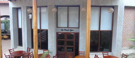An outdoor seating area with wooden tables and chairs, a covered patio, and a sign reading "Bar Circulo Negro".