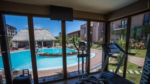 A hotel room with a large window overlooking a swimming pool and a fitness center. - Hotel Cubitá Boutique Resort & Spa (La Arena)