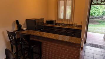 A kitchen with a granite countertop, a microwave, a coffee maker, and a brick backsplash.
