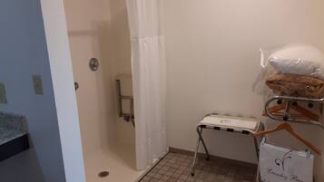 A bathroom with a shower, a towel rack, and a laundry bag hanging on the wall.