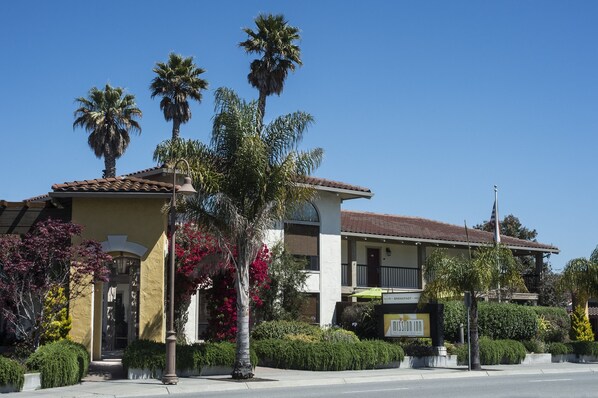 A two-story building with a tiled roof, a balcony, and a sign for a restaurant. - Mission Inn (Santa Cruz)