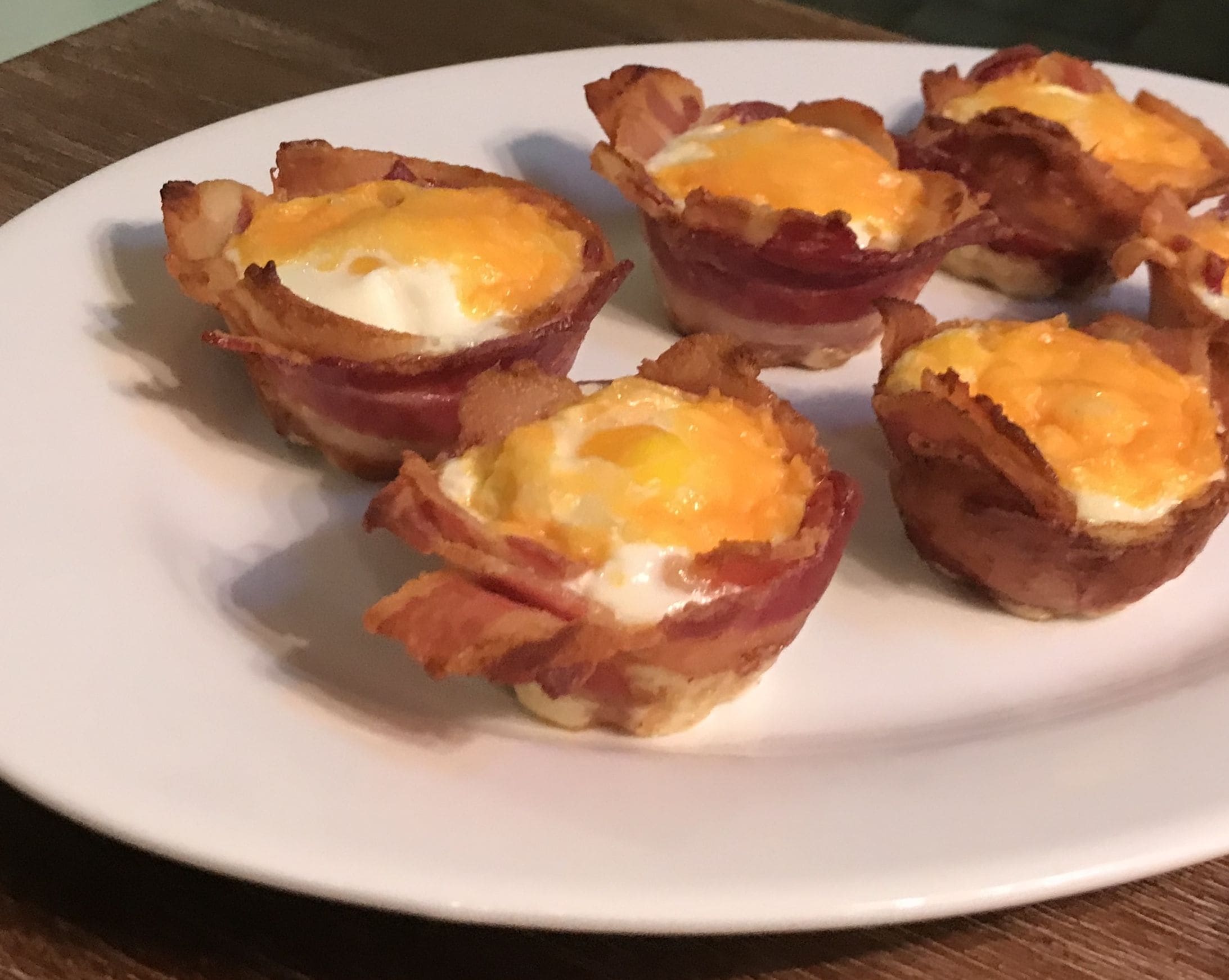 A plate with several bacon-wrapped eggs.