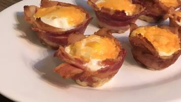 A plate with several bacon-wrapped eggs.
