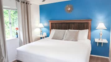 Una camera da letto con un letto grande, due comodini con lampade, una ventola a soffitto e una finestra con tende.