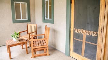 Un banco de madera y dos sillas frente a un edificio con un letrero que dice 'Welcome'.