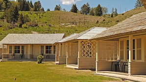 A row of cabins with a grassy yard and a hill in the background.