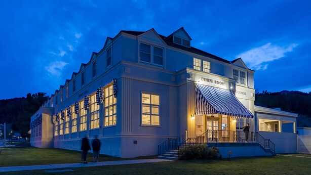 A large, two-story building with a dining room and lounge area, featuring large windows and a covered entrance.
