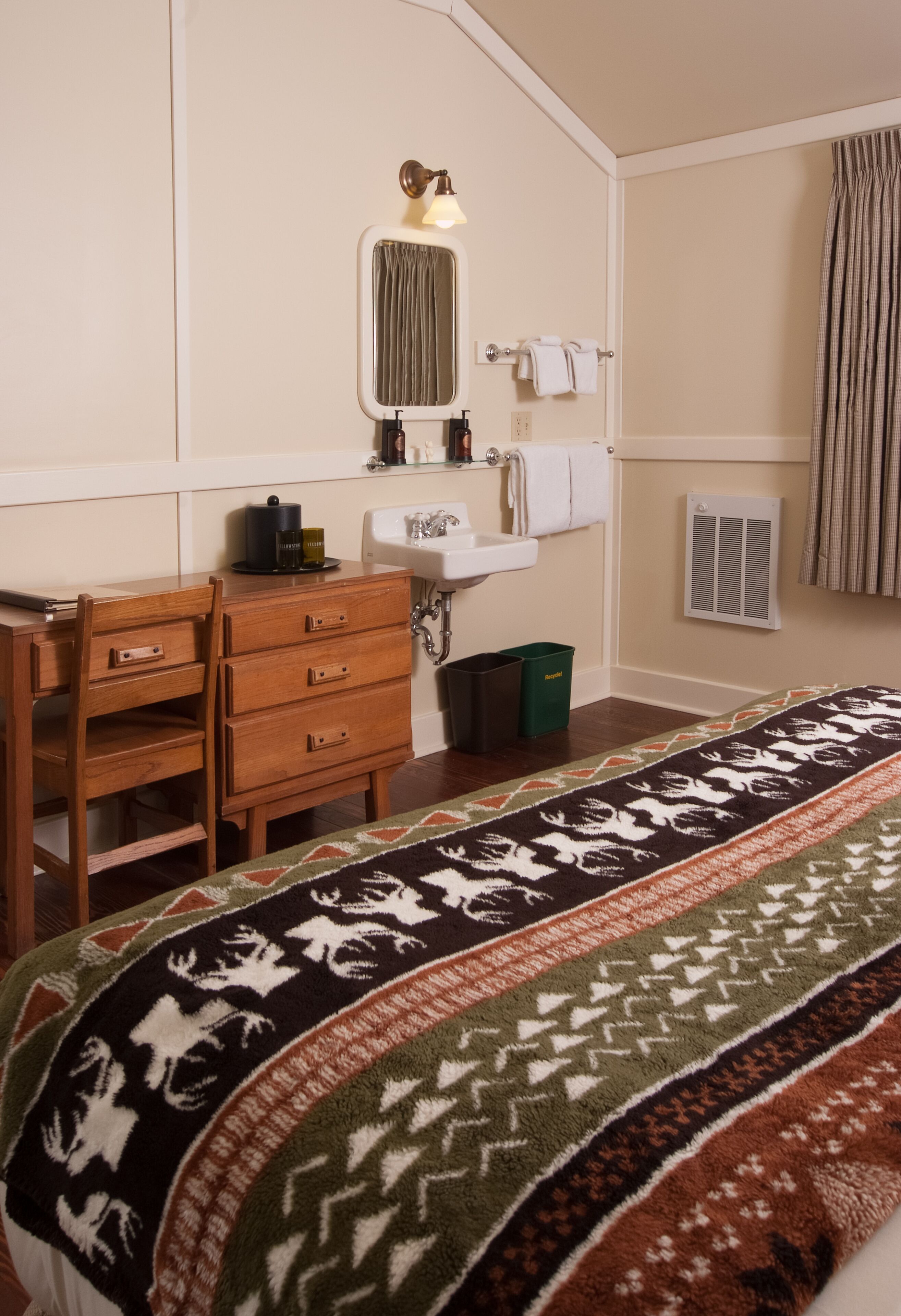 A bedroom with a wooden dresser, a mirror, a sink, and a patterned rug.
