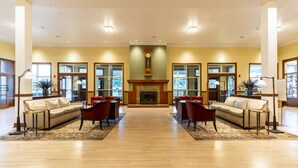 A spacious lobby with a fireplace, leather sofas, and a wooden floor.