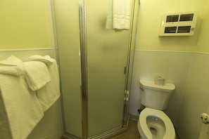 A bathroom with a glass-enclosed shower, a toilet, and a wall-mounted air vent. - Many Glacier Hotel - Inside the Park (East Glacier Park)