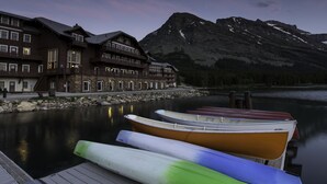 A lakeside hotel with a dock and boats, surrounded by mountains. - Many Glacier Hotel - Inside the Park (East Glacier Park)