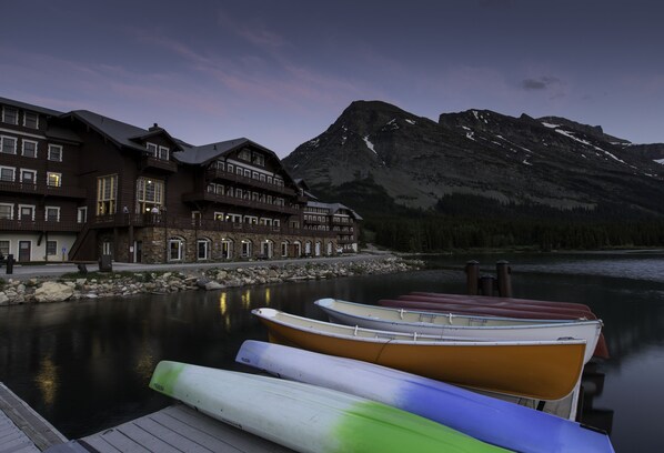 A lakeside hotel with a dock and boats, surrounded by mountains. - Many Glacier Hotel - Inside the Park (East Glacier Park)