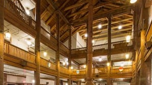 A spacious lobby with high ceilings, wooden beams, and multiple seating areas with red upholstered furniture.