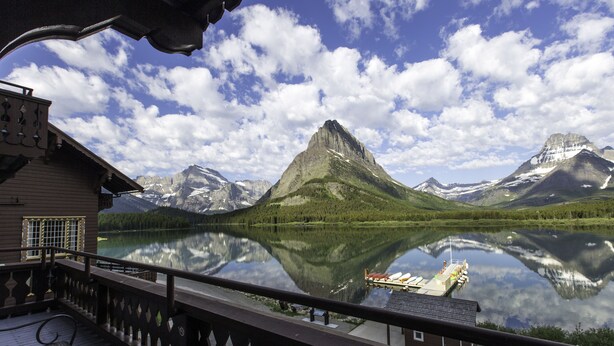 A lakeside view from a wooden deck with a mountain in the background.