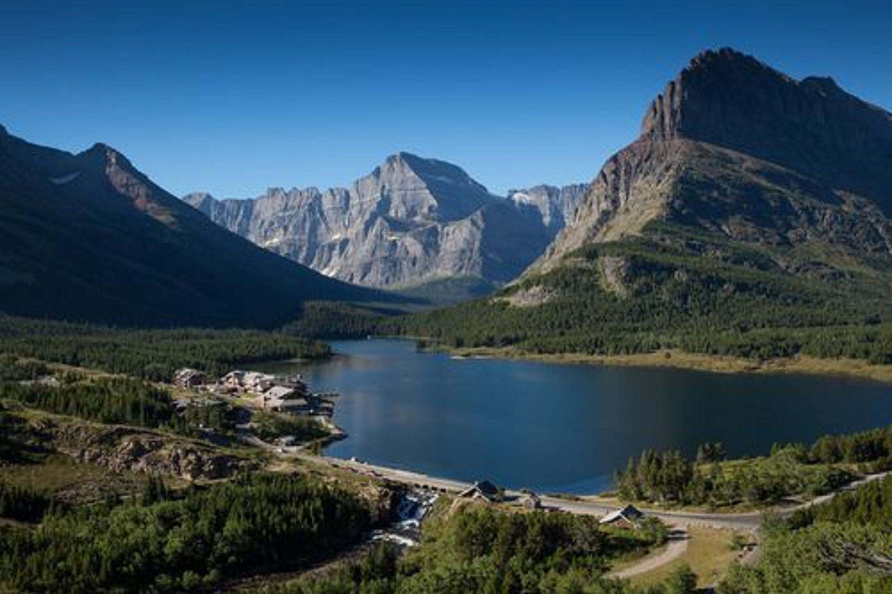 Ett bergigt landskap med en sjö, en liten bebyggelse och en framträdande bergstopp.