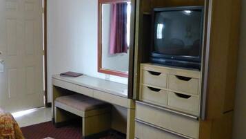 Una habitación pequeña con escritorio, televisión y una banca.