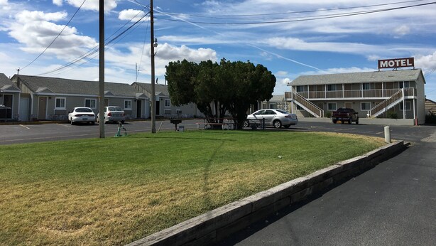 A motel with a sign, a parking lot, and a grassy area. - Umatilla Inn and Suites (Umatilla)
