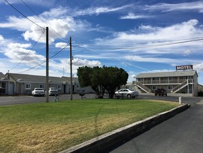 A motel with a sign, a parking lot, and a grassy area.