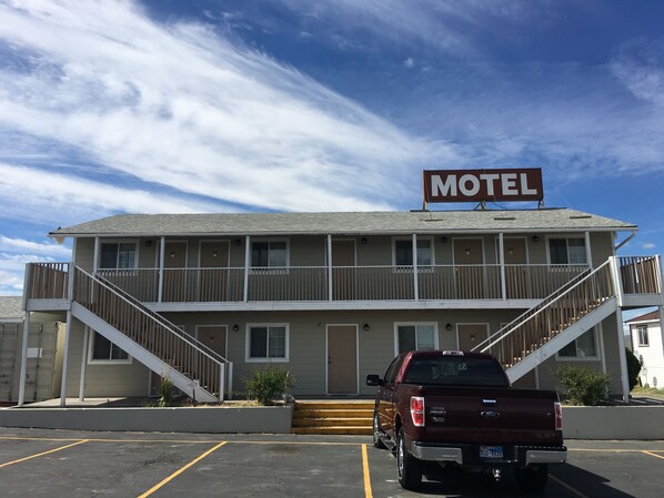A motel with a two-story structure, a signboard, and a parking lot with a parked truck.
