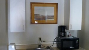 A kitchen with a microwave, coffee maker, and a framed picture on the wall. - Umatilla Inn and Suites (Umatilla)