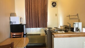 A compact kitchenette with a microwave, stove, sink, and coffee maker. - Umatilla Inn and Suites (Umatilla)