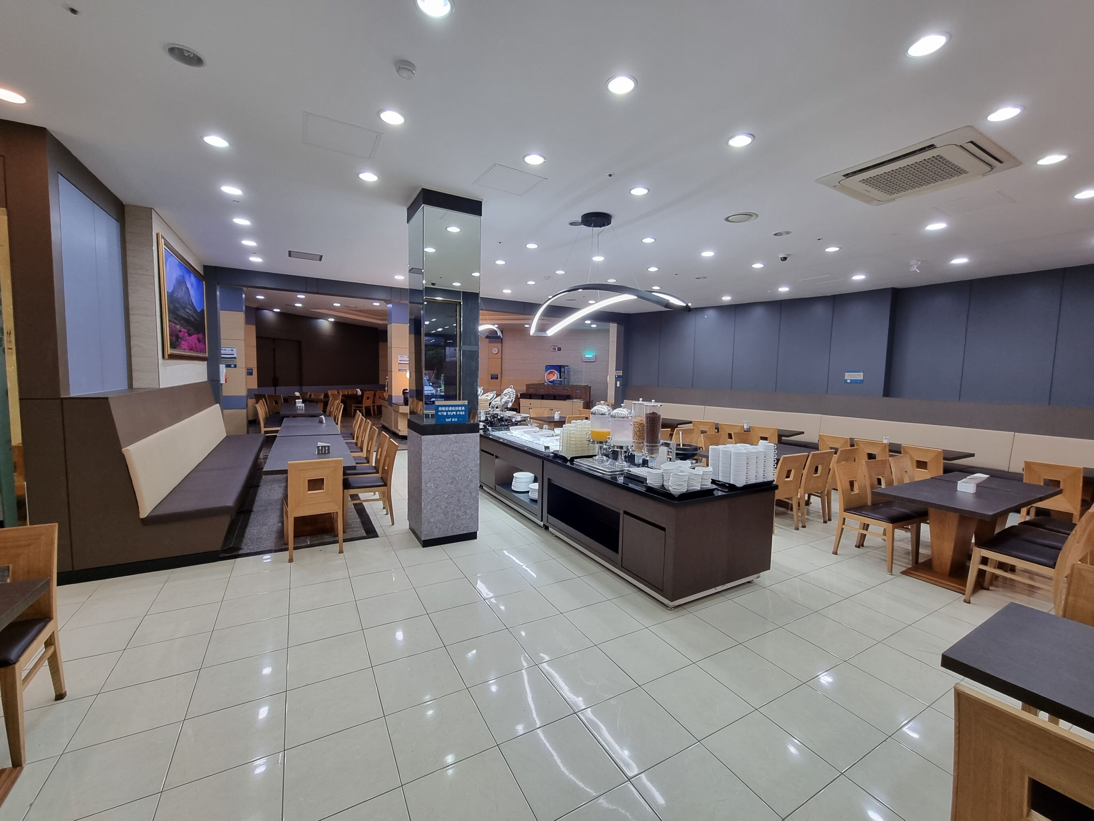Un restaurante moderno con un mostrador central, varias zonas de estar y un suelo de baldosas limpias.