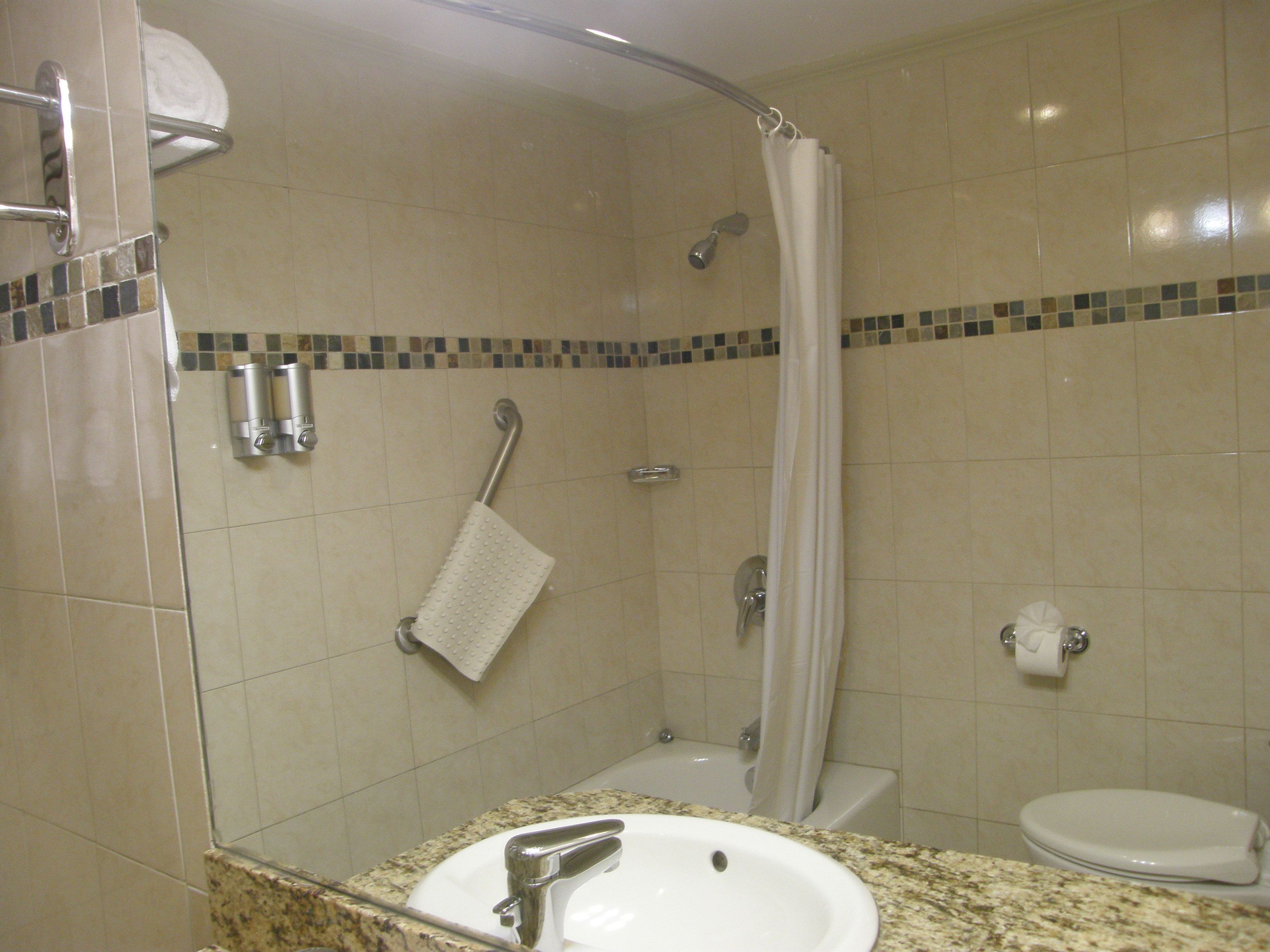 A bathroom with a sink, toilet, shower, and a towel rack.
