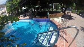 A swimming pool with a tiled edge, a metal handrail, and a brick patio area. - Hotel Four Seasons (Kingston)