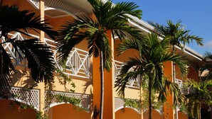 A building with a yellow facade, white lattice balconies, and palm trees. - Hotel Four Seasons (Kingston)