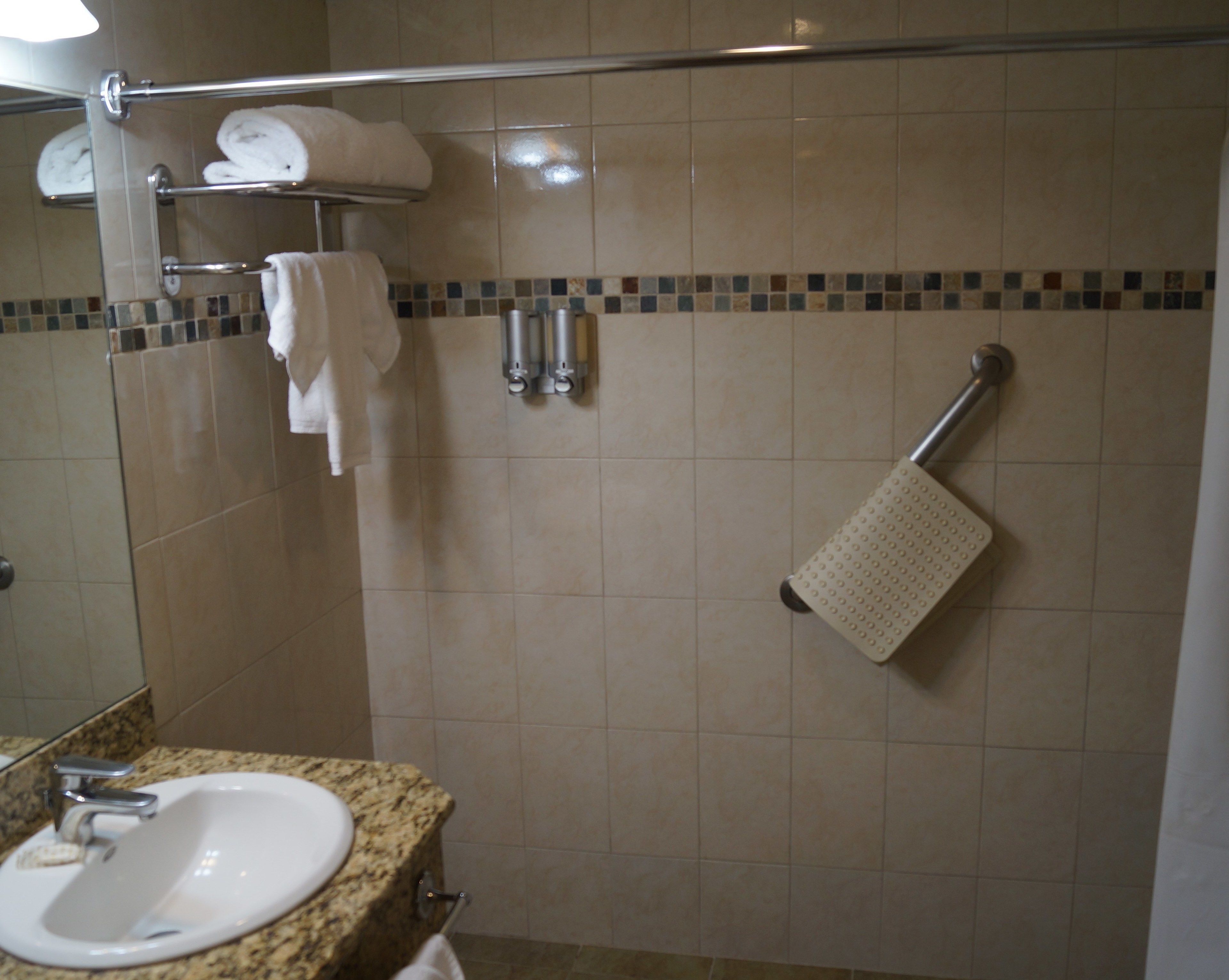 A bathroom with a sink, towel rack, and shower area.