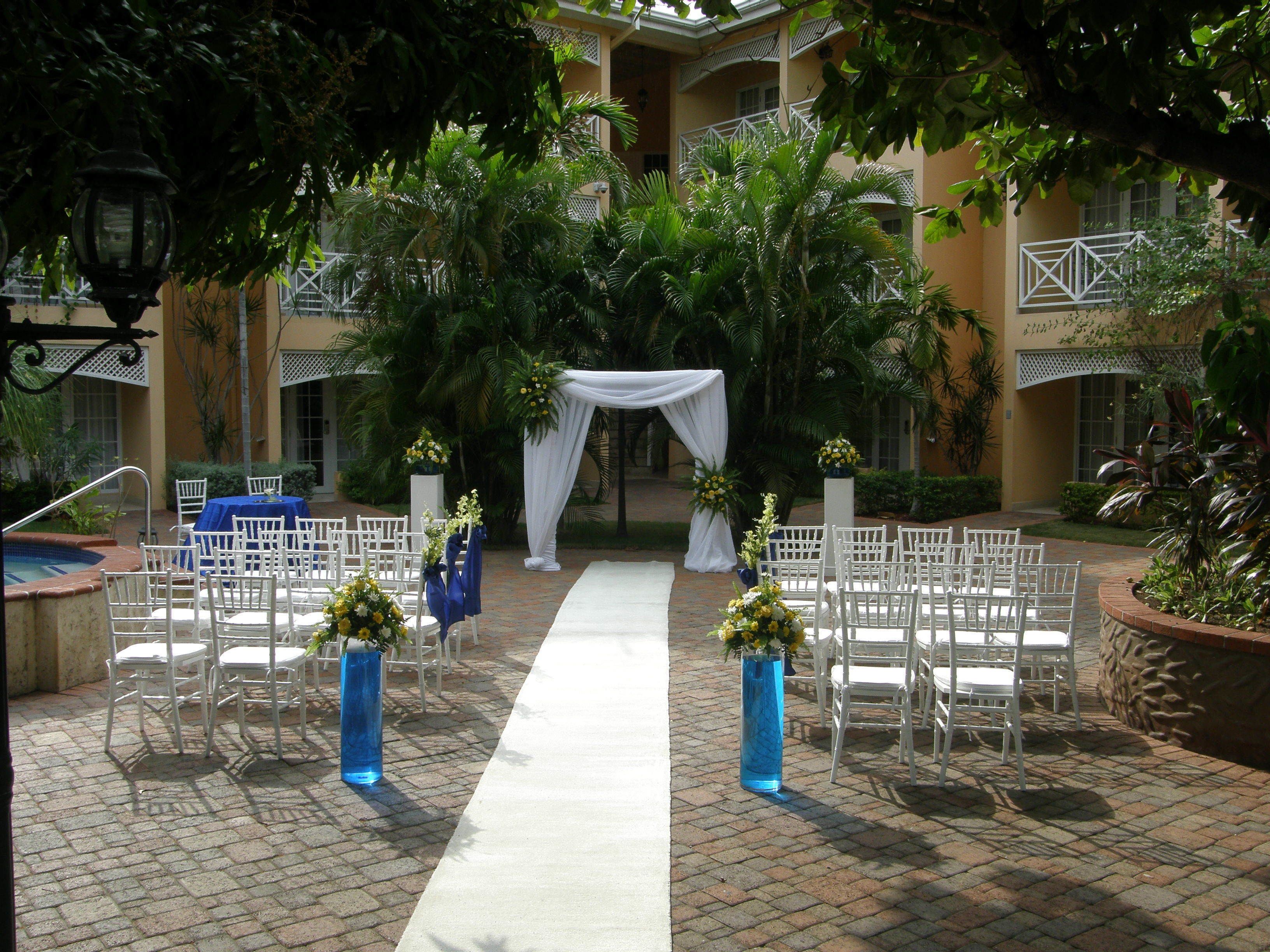 An outdoor wedding venue with white chairs and a white aisle.