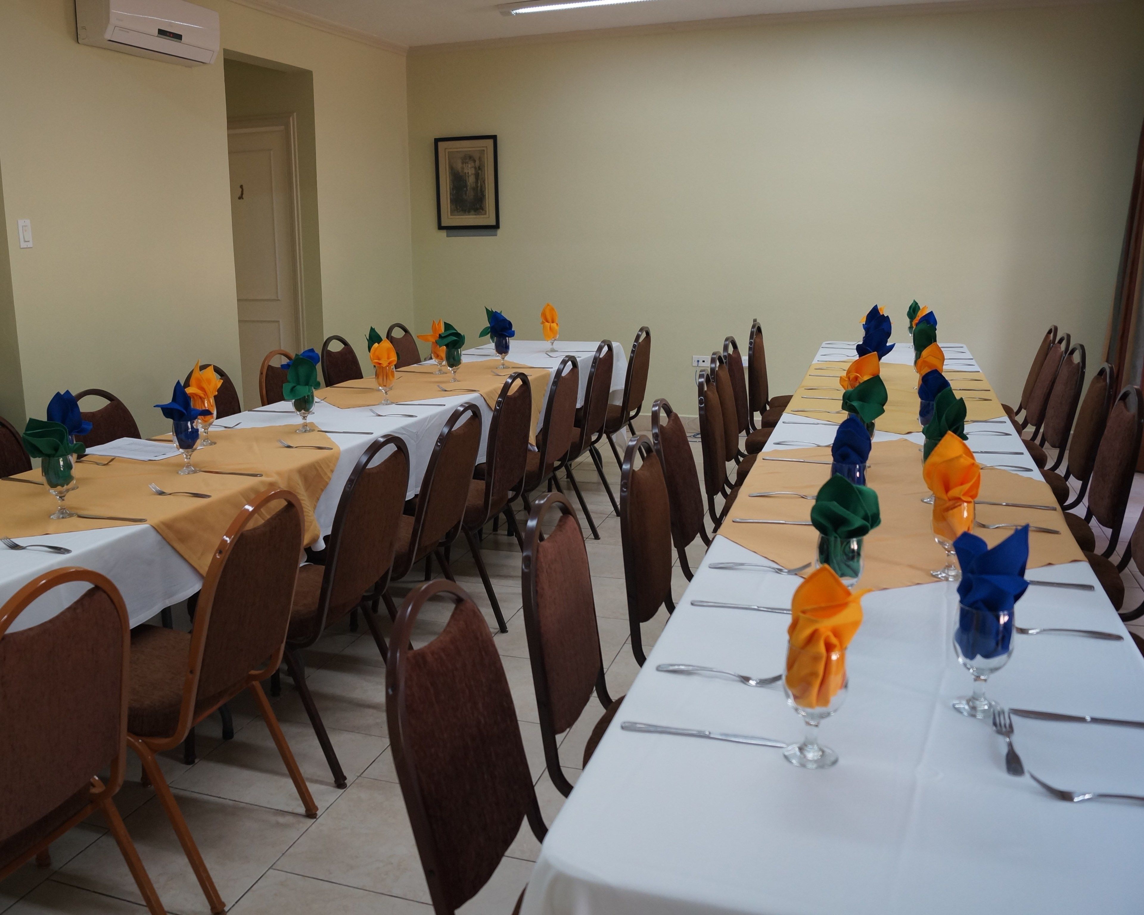 A conference room with long tables set for a meeting, equipped with chairs and tables.