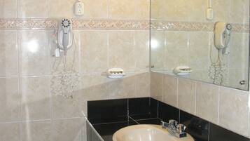 Un baño con lavamanos, espejo y toallero.