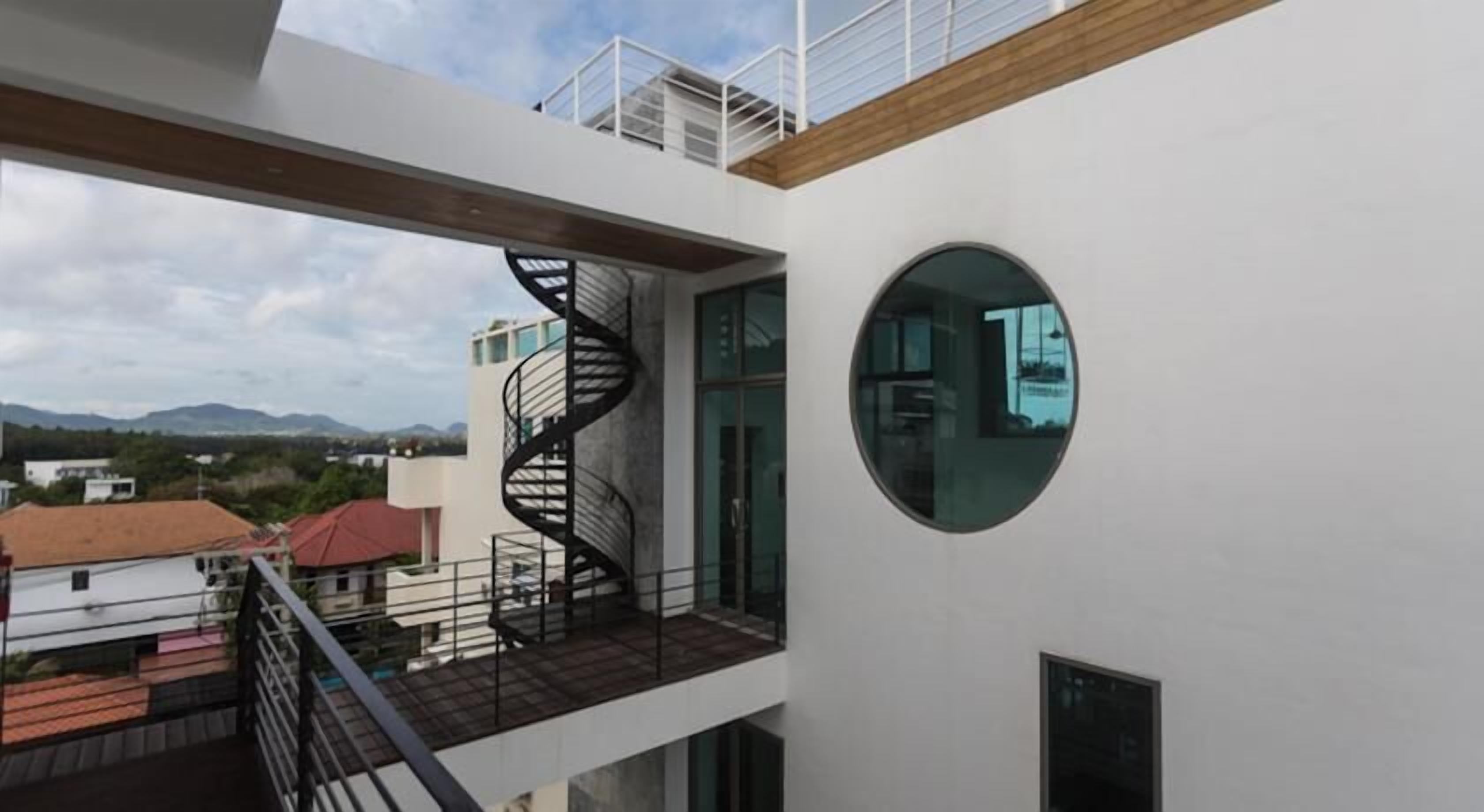 A modern building with a spiral staircase, a round window, and a view of the surrounding area.