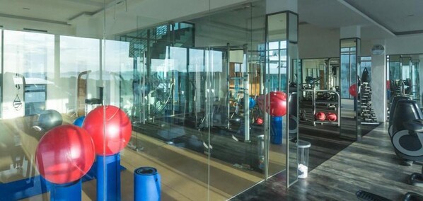 A gym with exercise equipment, including weights and exercise balls, and a mirrored wall. - Action Point Fitness Resort (Rawai)