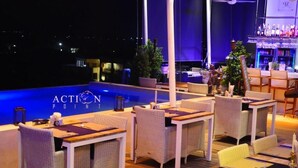 Eine Dachterrasse mit Korbmöbeln und Blick auf den Pool.