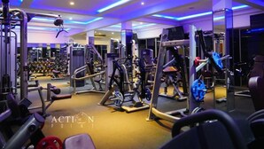 Ein Fitnessstudio mit verschiedenen Trainingsgeräten, darunter Laufbänder und Kraftmaschinen, beleuchtet mit blauem Licht.