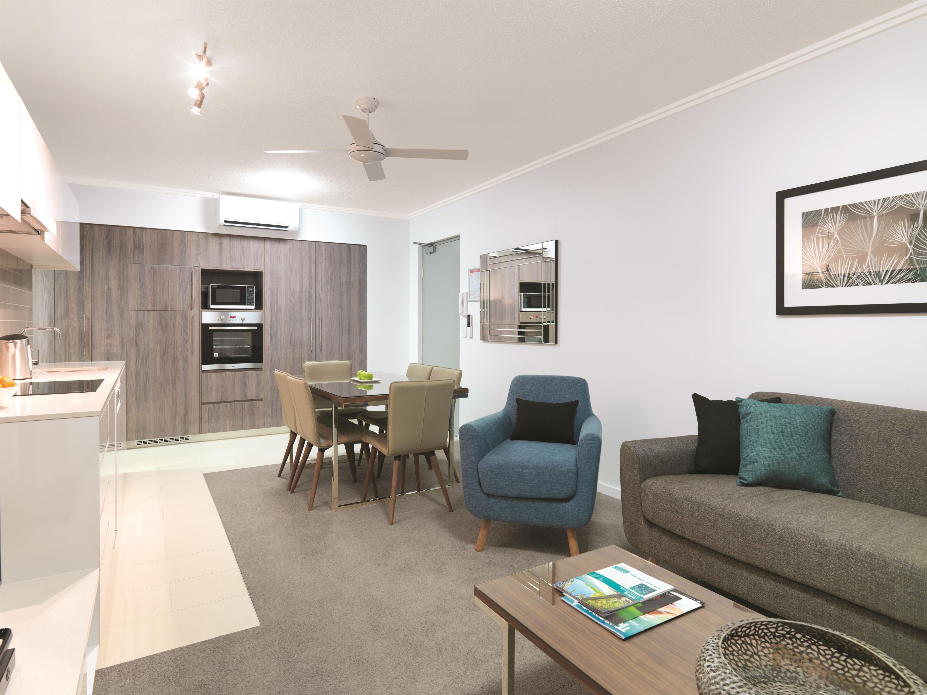 A modern living room with a sofa, armchair, coffee table, and a dining area with chairs and a table.