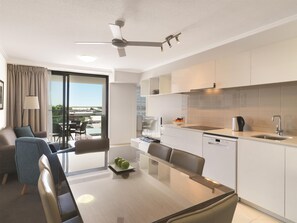 Una habitación de hotel moderna con balcón, zona de comedor y kitchenette.
