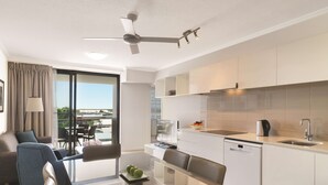 A modern hotel room with a balcony, a dining area, and a kitchenette. - Oaks Mackay Carlyle Suites (Mackay)
