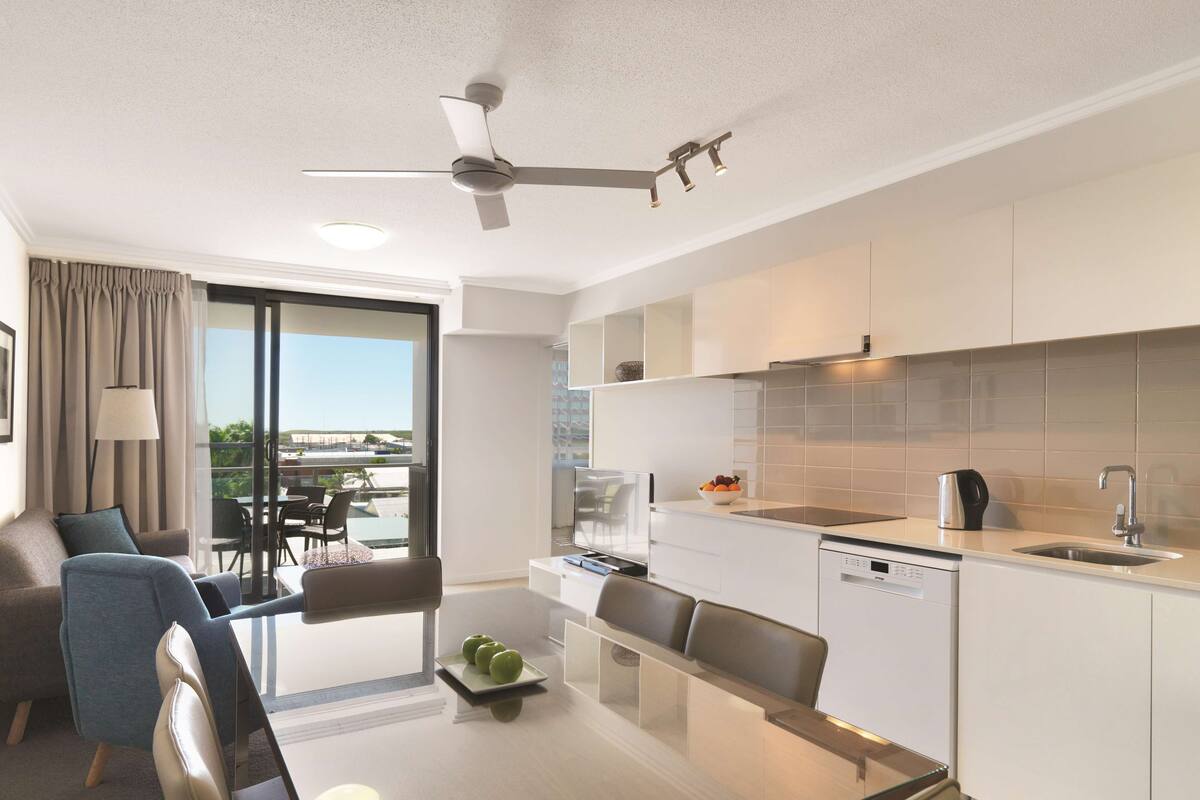 Ein modernes Hotelzimmer mit Balkon, Essbereich und Küchenzeile.