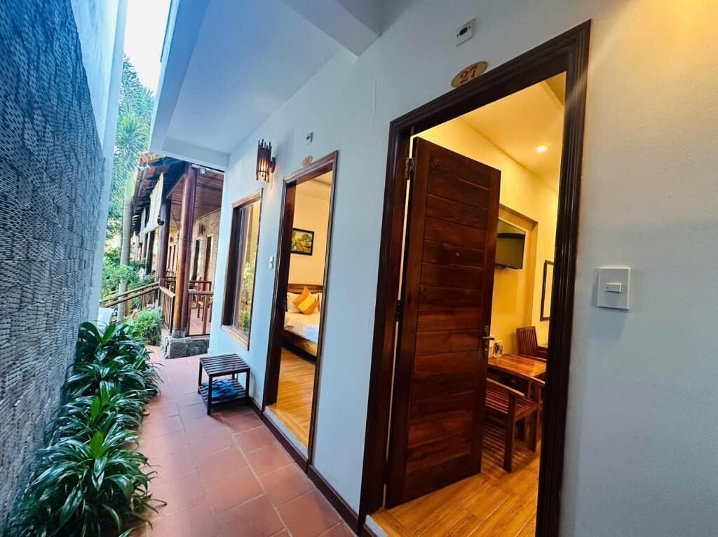 A corridor with wooden doors, a bench, and potted plants.