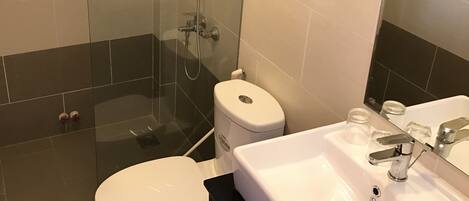 Une salle de bain moderne équipée de toilettes, d’un lavabo et d’une douche à parois de verre.