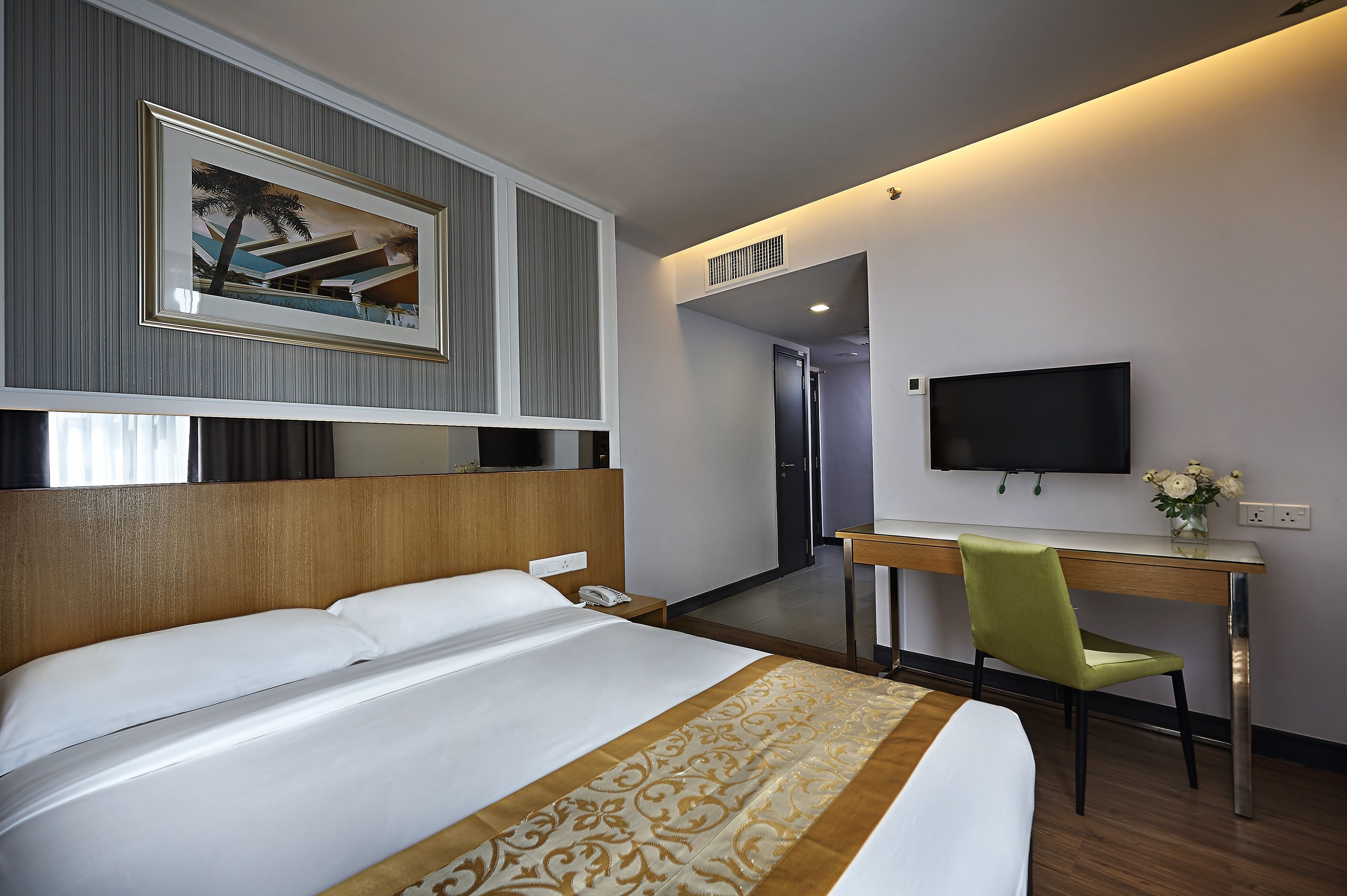 A hotel room with a bed, a desk, a chair, a TV, and a painting on the wall.