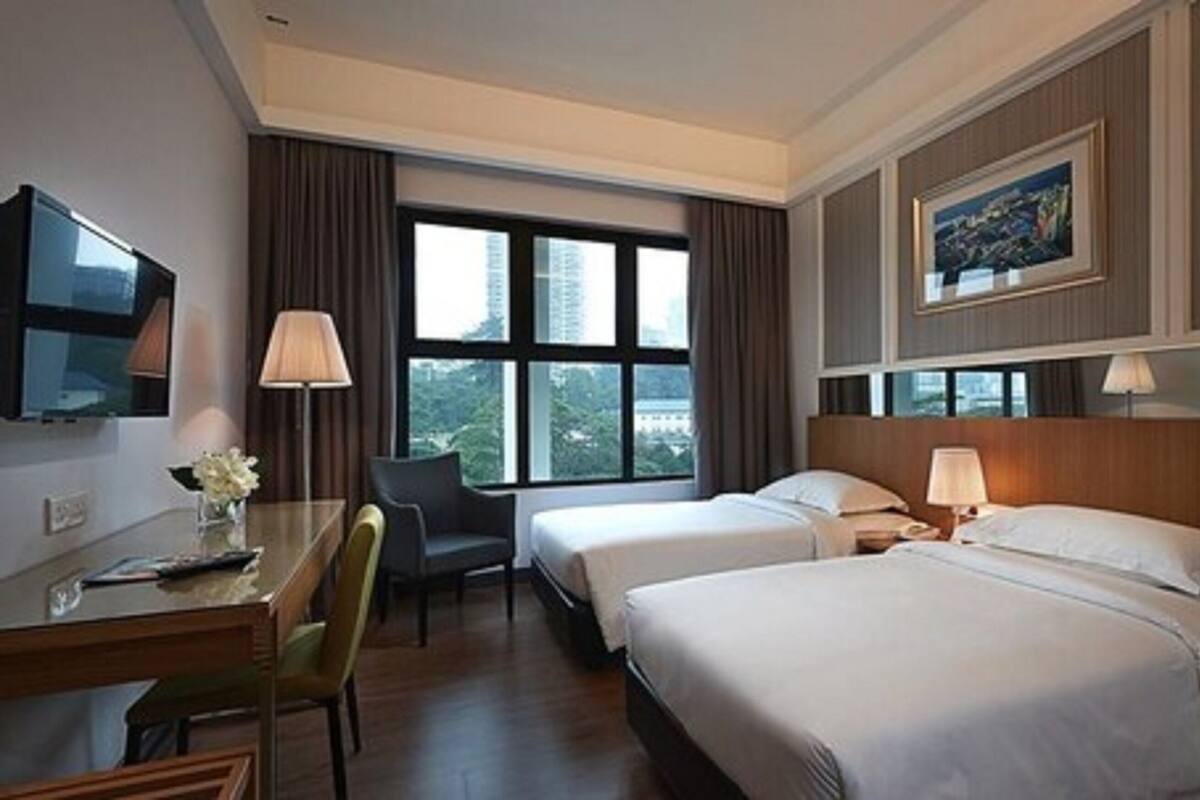 A hotel room with two beds, a desk, a chair, a TV, and a window with a city view.