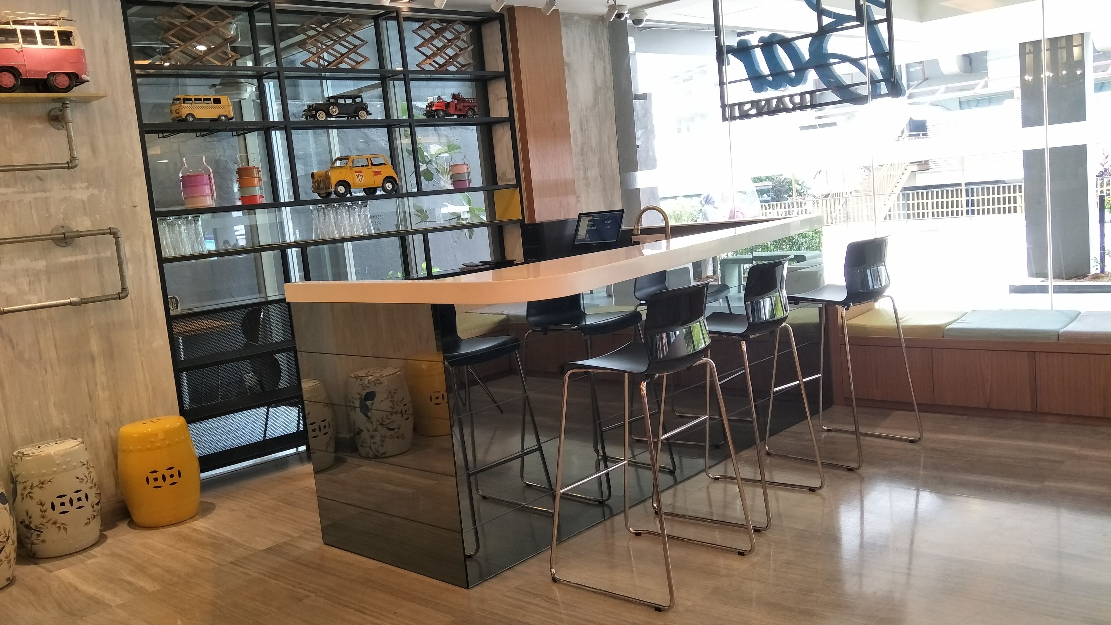 A modern bar area with a wooden counter and black bar stools.