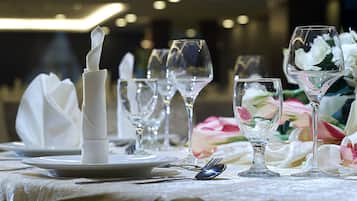 A table set with white napkins, clear wine glasses, and a floral arrangement.
