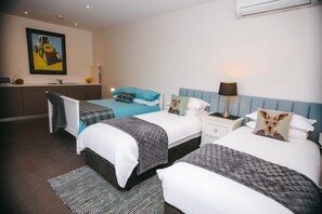 Two single beds with matching headboards, a bedside table, and a large window create a calm and welcoming space.